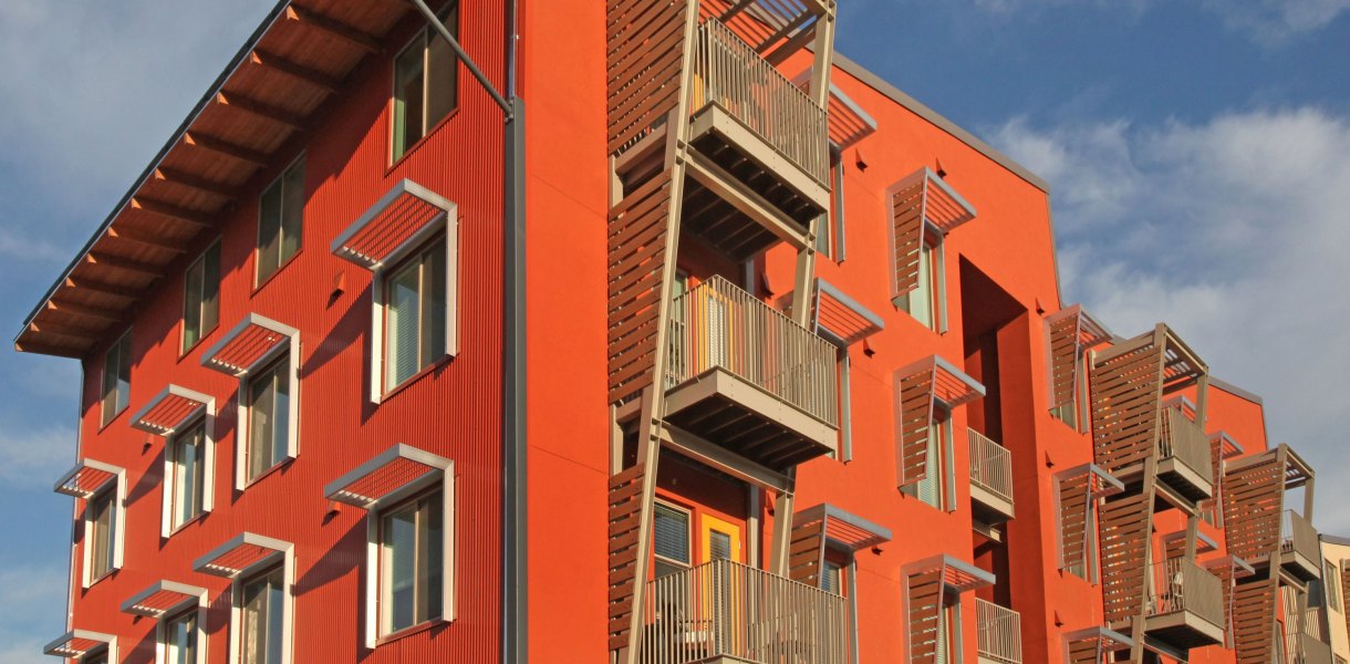 UC Davis West Village residential building with a vibrant orange facade and multiple balconies.